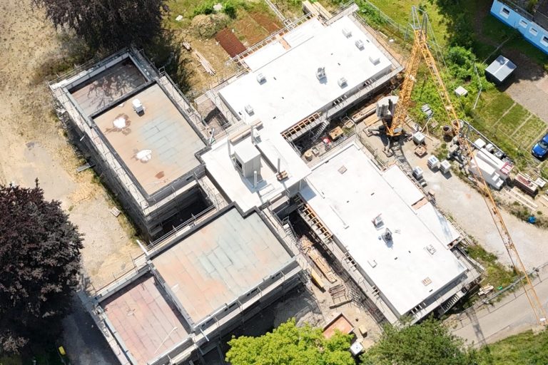 Bauprojekt mit mehreren Gebäuden und Baustellenmaterial im Freien.
